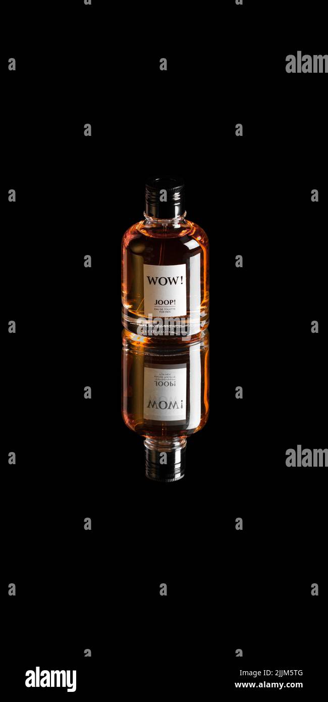 A vertical shot of a Joop WOW Parfum on a mirror on black isolated background Stock Photo