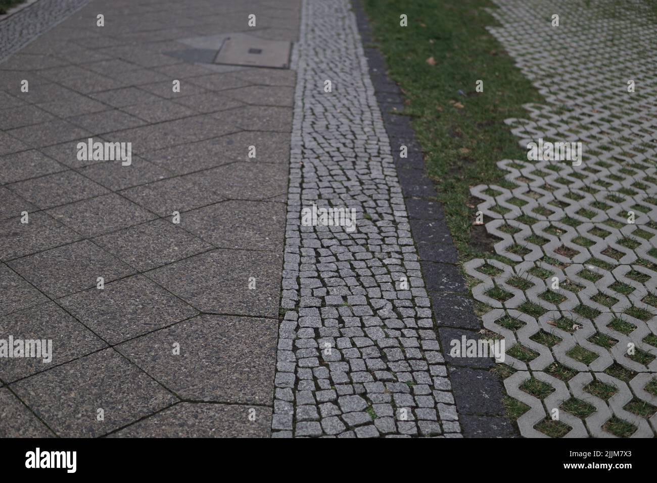 A beautiful shot of a Detailed closeup texture on a cobblestone street with different tiles and grass Stock Photo