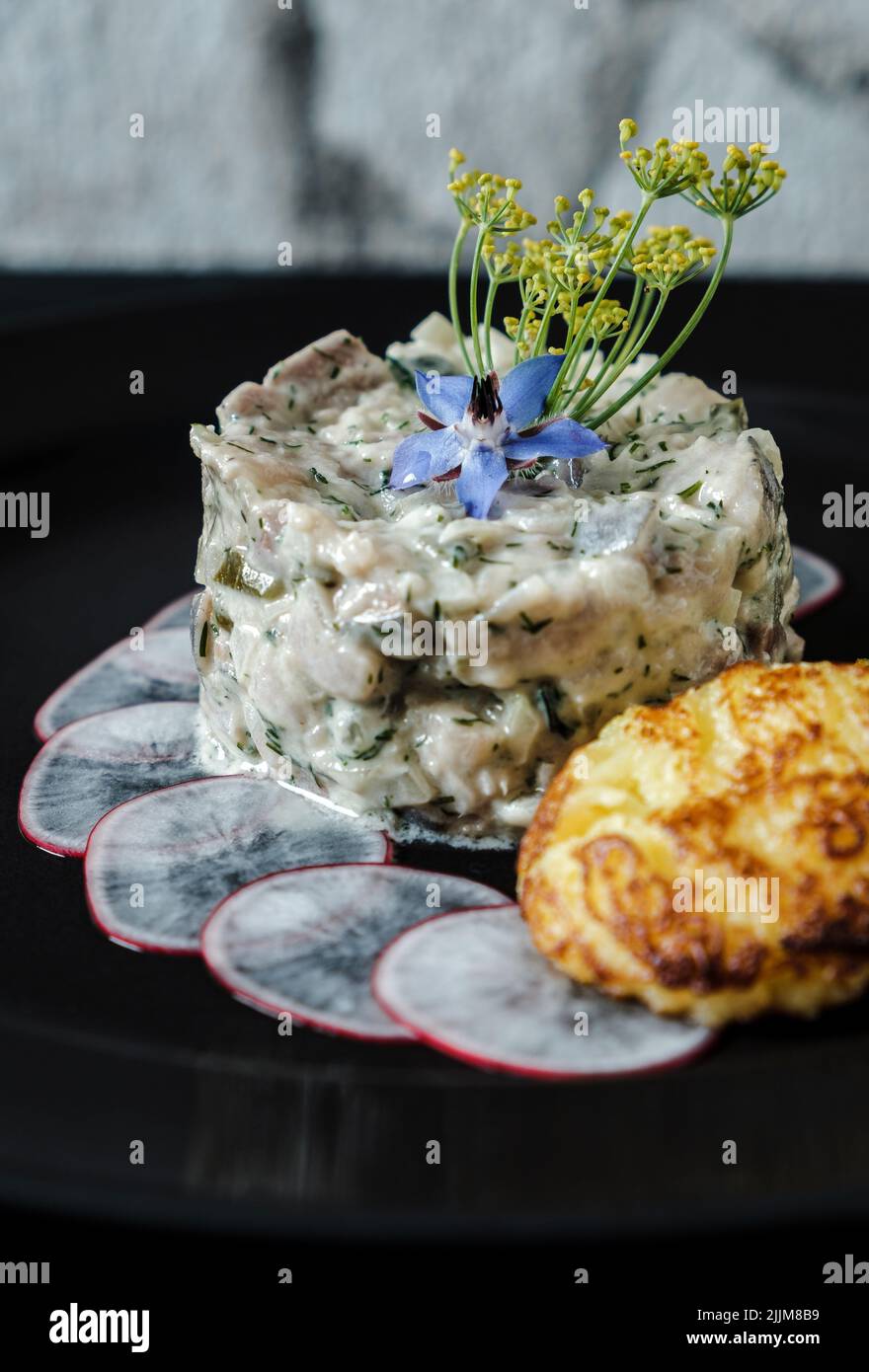A vertical shot of tasty matjes tartare with potato fritters and ...