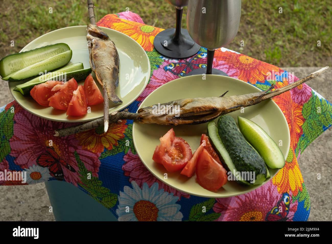 Picnic table in the garden with grilled fish and vegetables Stock Photo