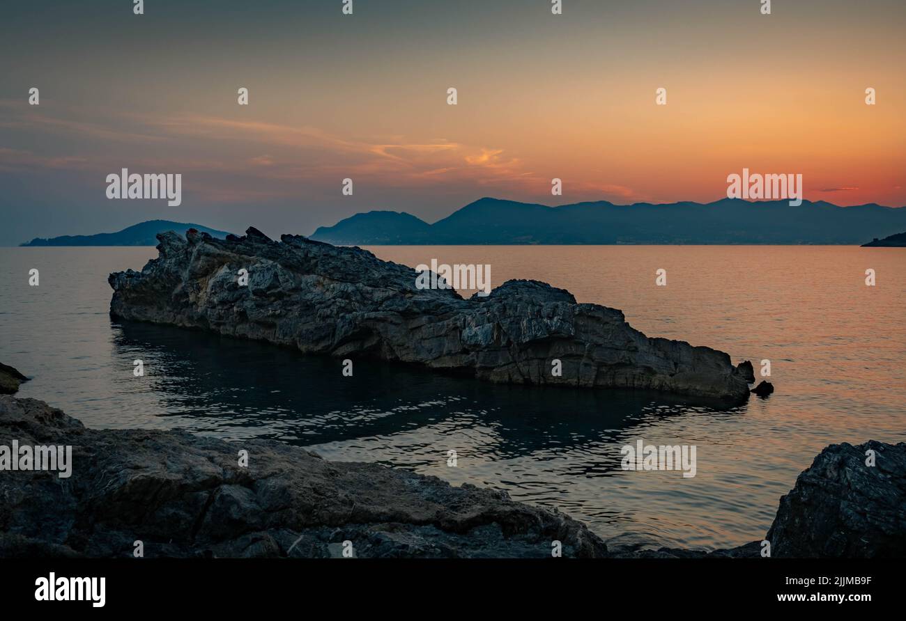Picture of a rock emerging from the sea during a sunset Stock Photo - Alamy