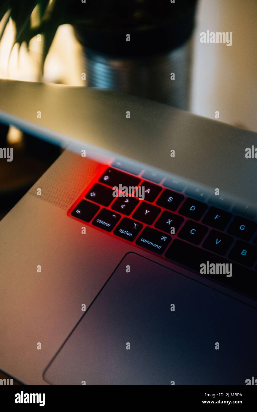 A vertical shot of a laptop with a keyboard with red lights Stock Photo