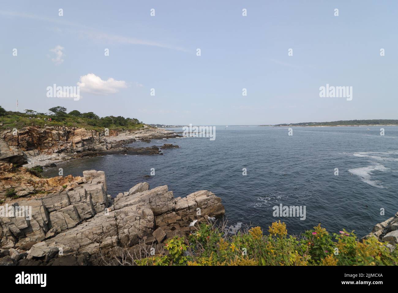 A natural view of a rocky coast under a clear blue sky during summertime Stock Photo