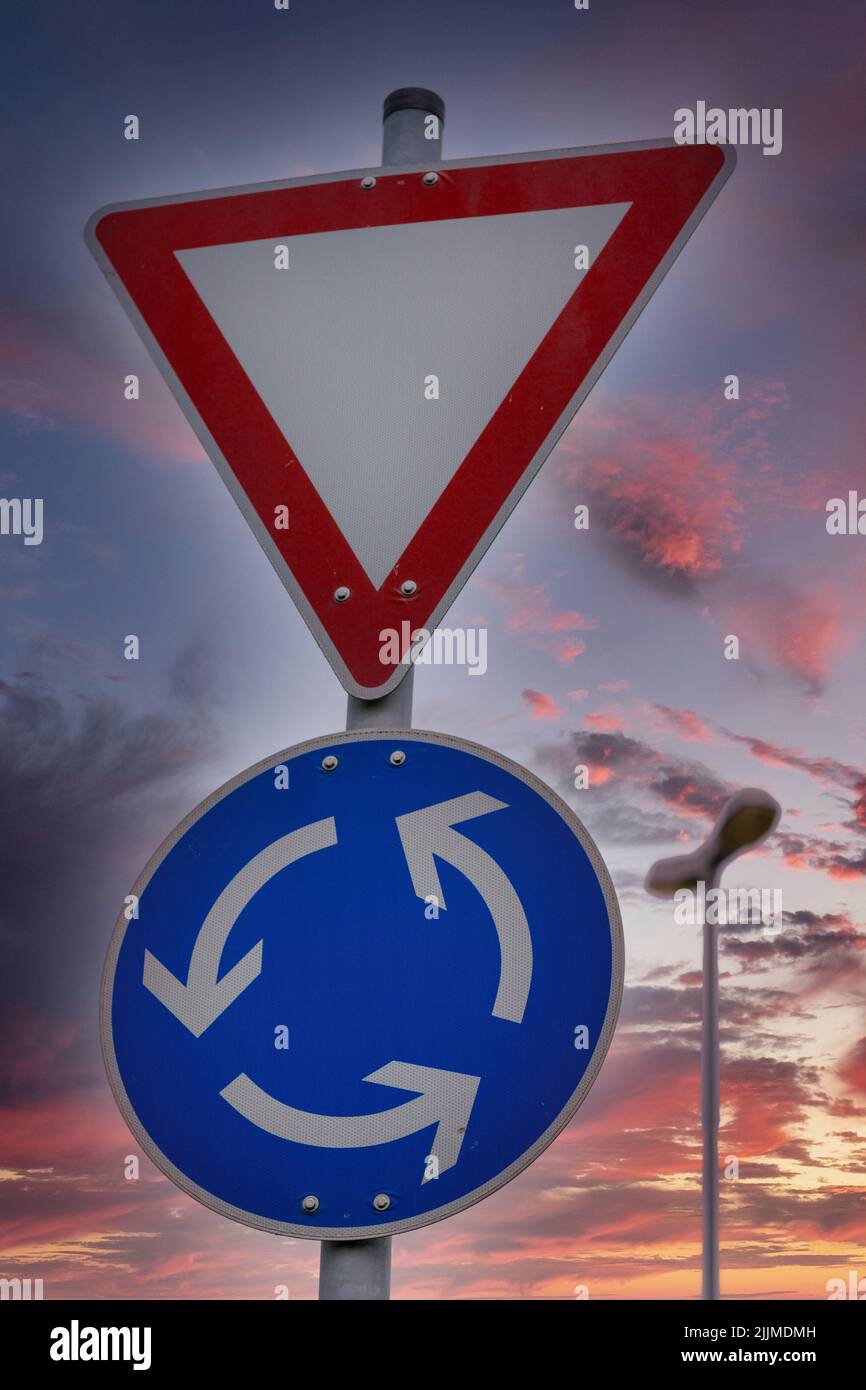 A vertical shot of the Yield and Roundabout road signs with a beautiful