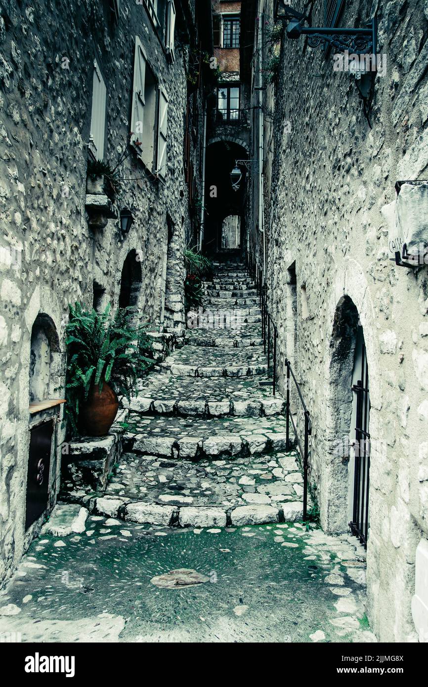 A vertical grayscale shot of a stone alley in Dorf, France Stock Photo