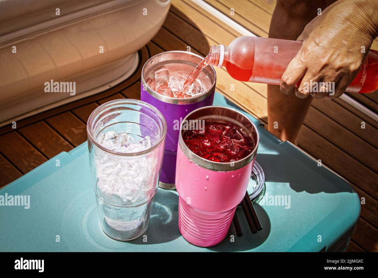 Boat Drinks poured from a bottle into insulated glasses with ice sitting on an ice chest on a luxury boat. Stock Photo