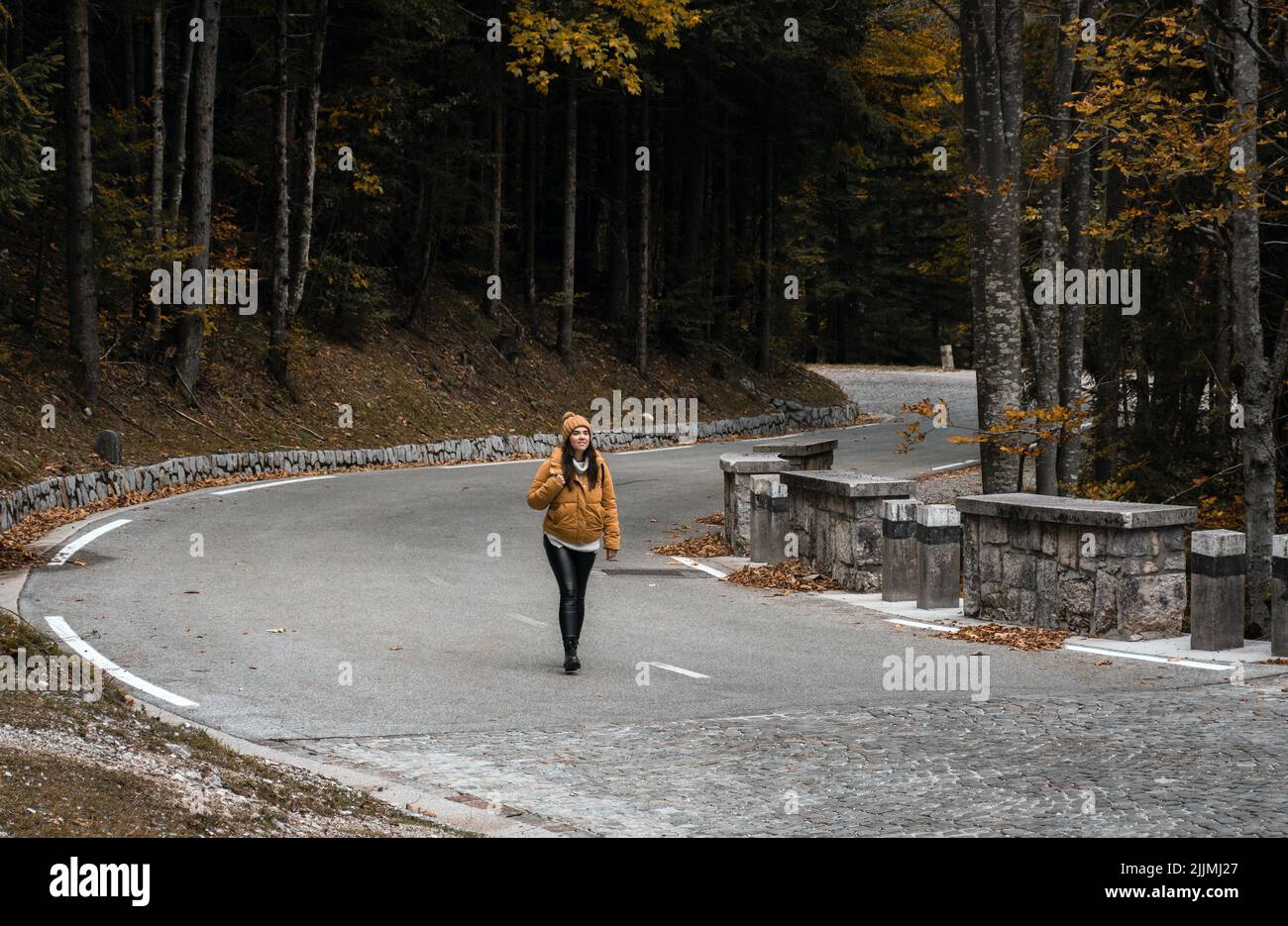 A female hiker walking on an empty road on Vrsic mountain pass in the Alps, Slovenia Stock Photo