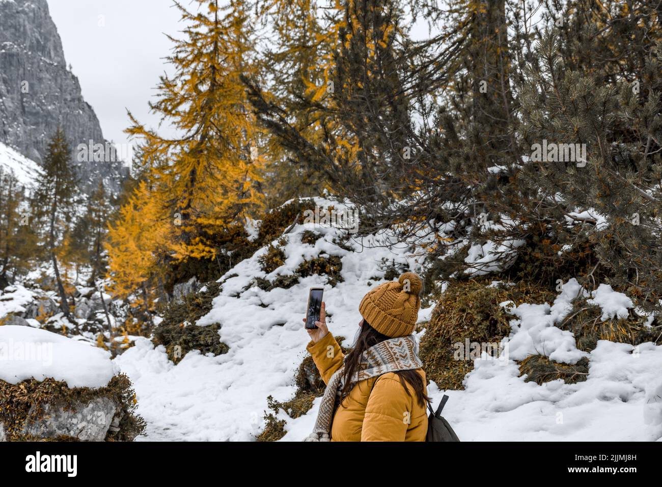 A female hiker wearing winter clothes, taking photos in a mountain in the Alps, Slovenia Stock Photo