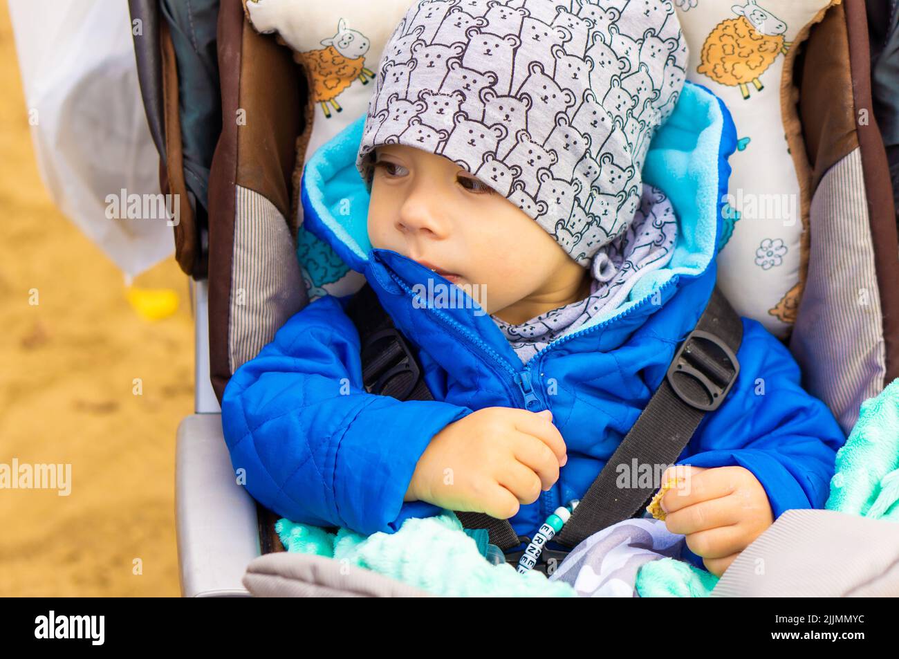 A small Caucasian young boy sitting in a buggy wearing a hat in Poznan, Poland Stock Photo