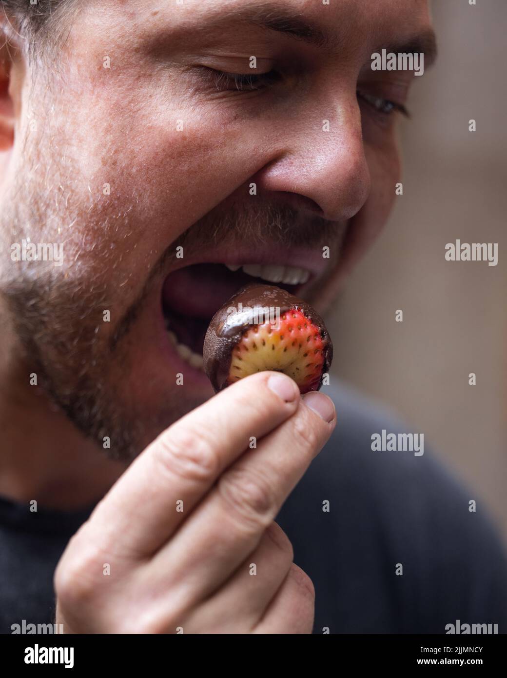 Man eating a chocolate covered strawberry close up portrait Stock Photo