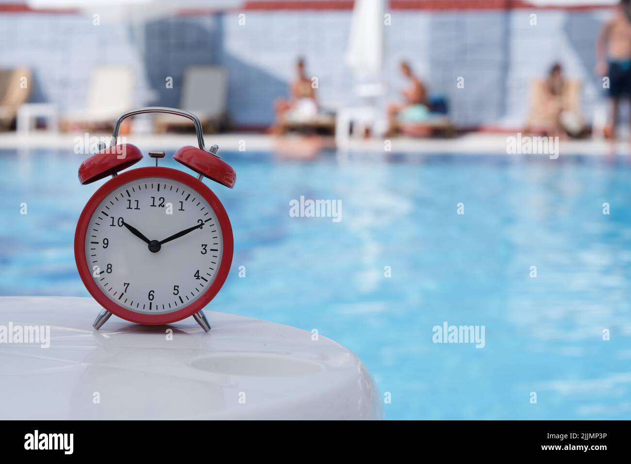 Red alarm clock for ten o'clock near pool in hotel or spa center Stock Photo