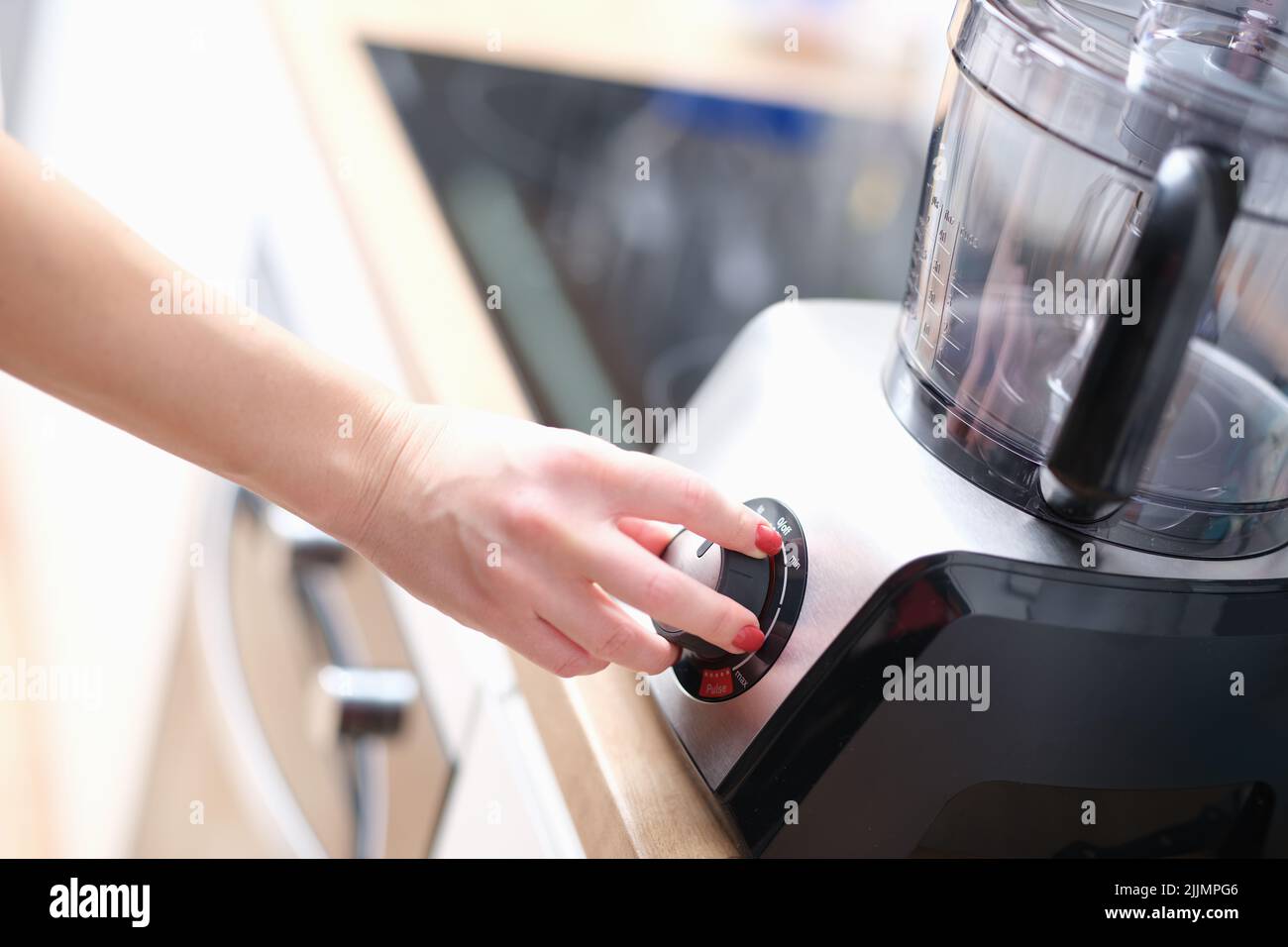 Woman hand presses start of food processor closeup Stock Photo