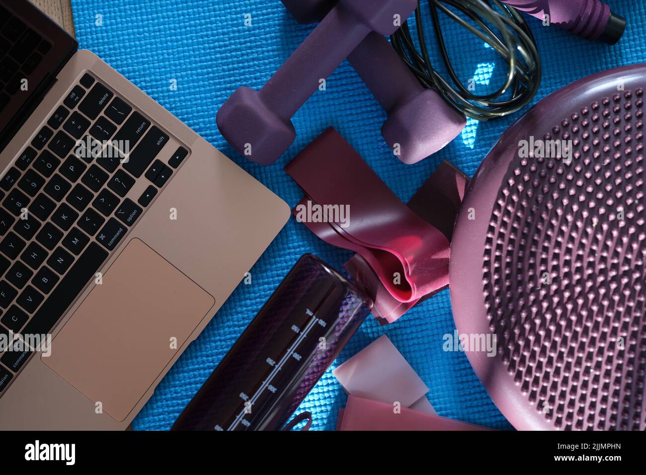 Laptop with purple sports equipment on sports mat top view Stock Photo
