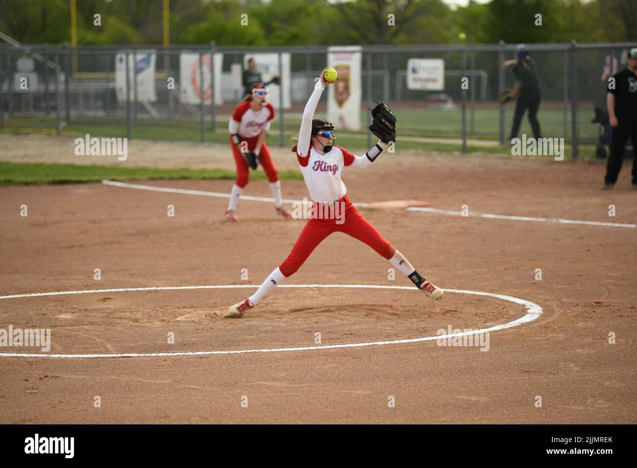 A view of a women's team in red and white uniform playing softball in the playground Stock Photo