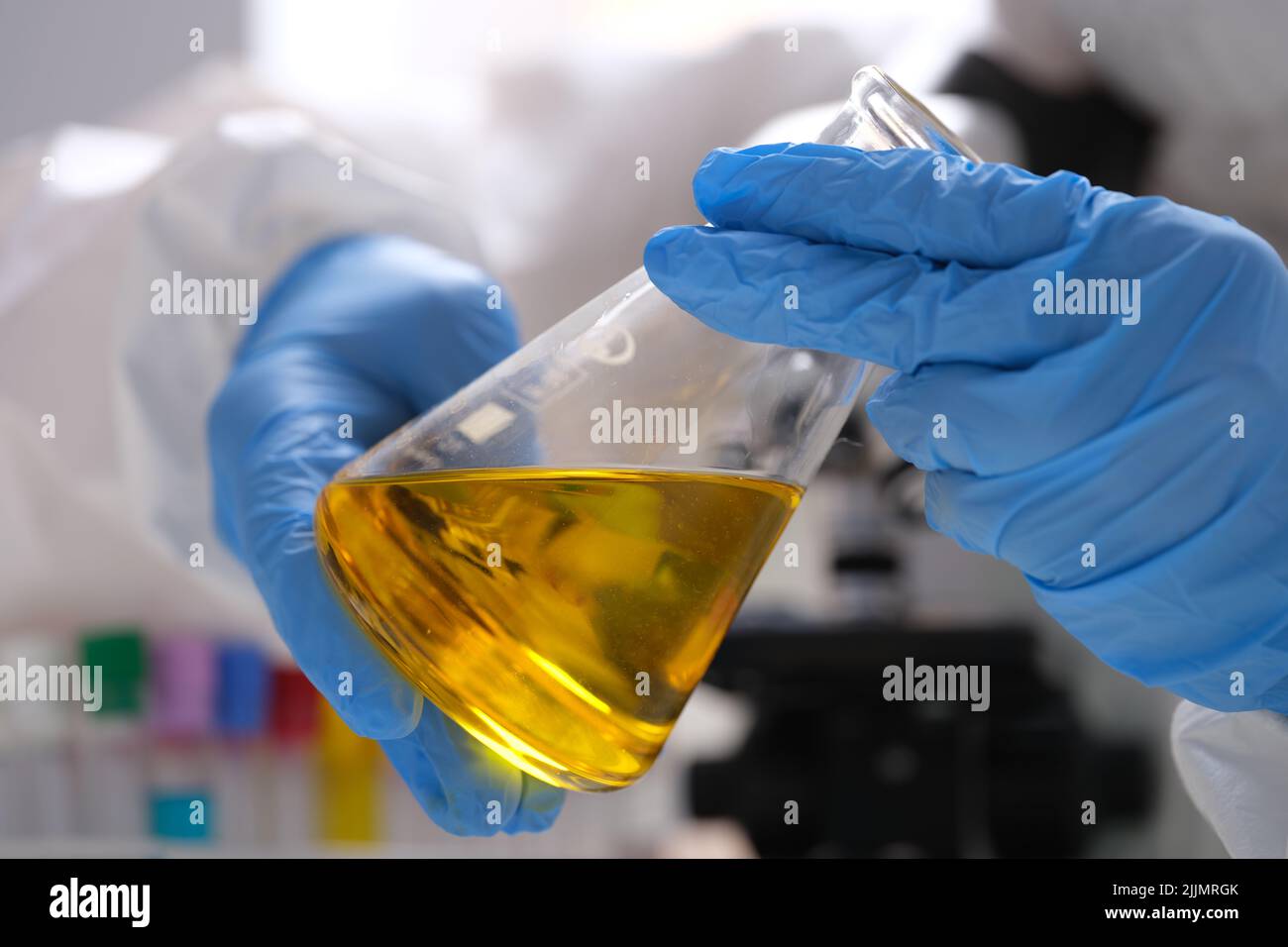 Chemist in gloves holds test tube with yellow oily liquid for research closeup Stock Photo