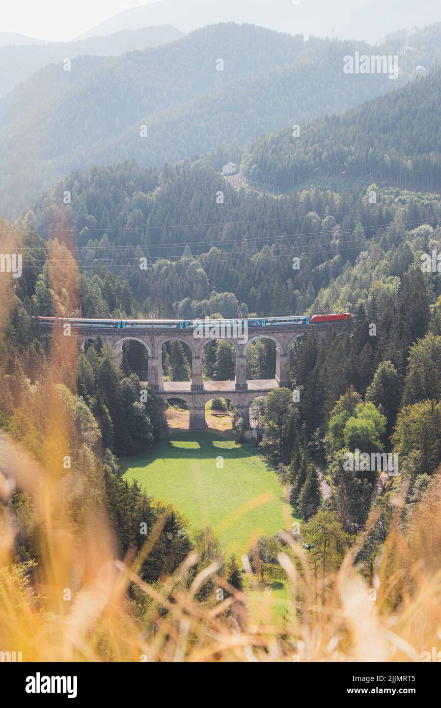 View of the Kalte Rinne railway viaduct and a passing train in Semmering, Rax-Schneeberg Group, Styria, Austria. Stock Photo