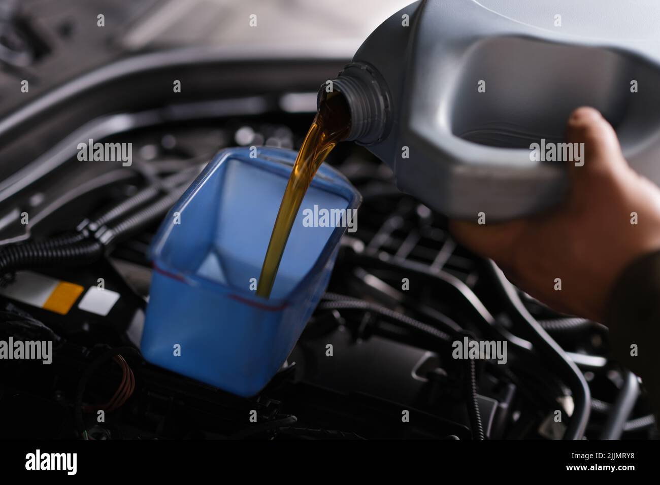 Auto mechanic replaces and pours fresh oil into engine at service station Stock Photo