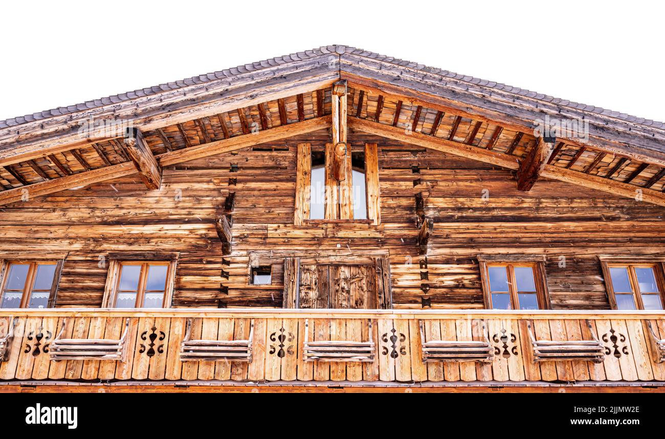 A low angle shot of a wooden house balcony with falling snow, Rauris ski center, Austria and light sky Stock Photo