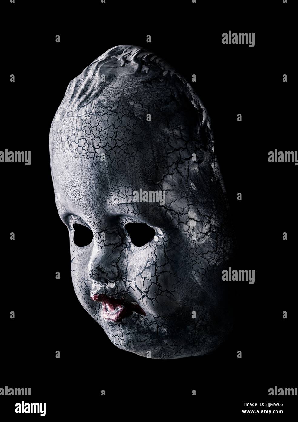 Old cracked creepy doll head isolated on black background Stock Photo