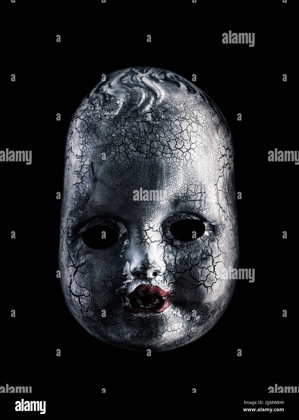 Old cracked creepy doll head isolated on black background Stock Photo