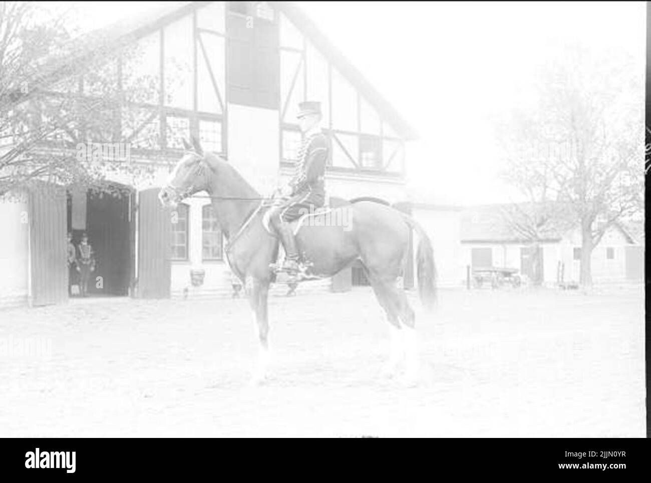 Livhusar (probably horse caretaker) on officers' service horse outside