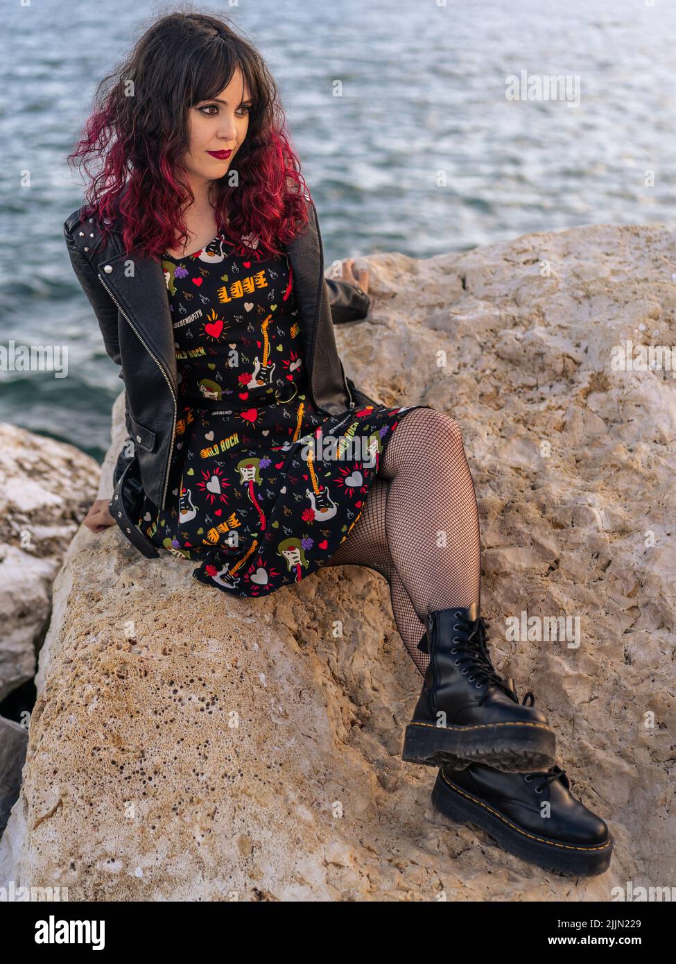 A fashionable Spanish woman with urban style posing on the breakwater in Malaga, Spain Stock Photo