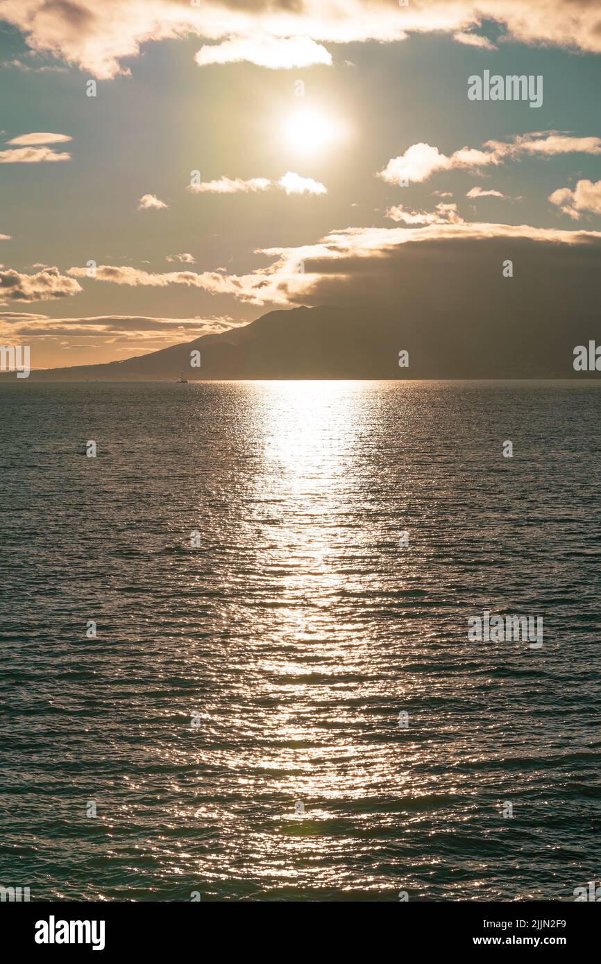 A scenic view of sunlight reflecting on sea water at sunset Stock Photo ...