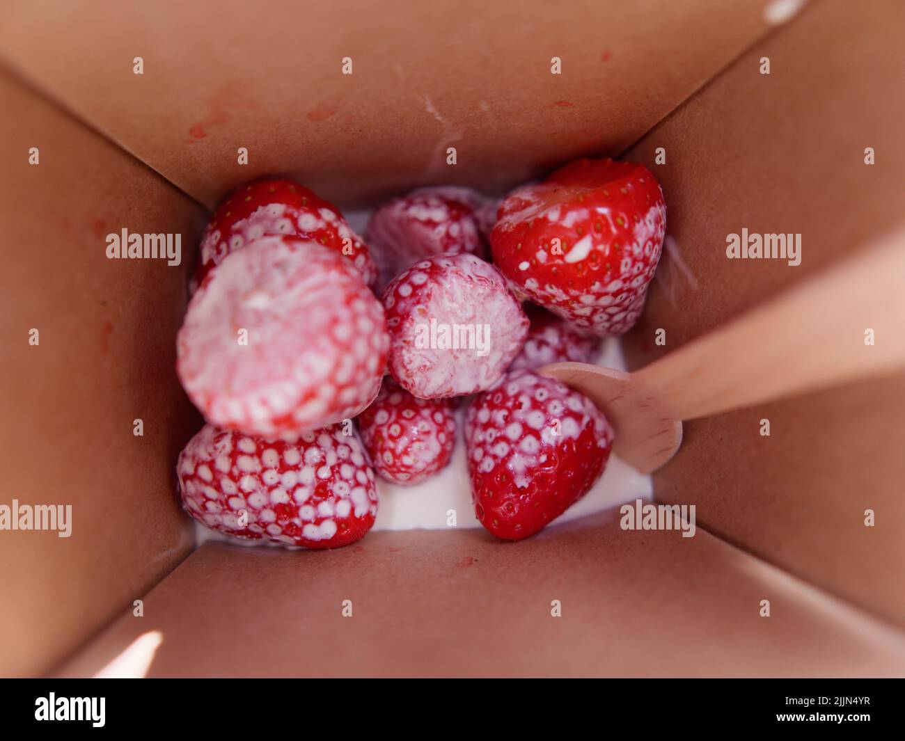 Strawberries and cream with a wooden spoon Stock Photo