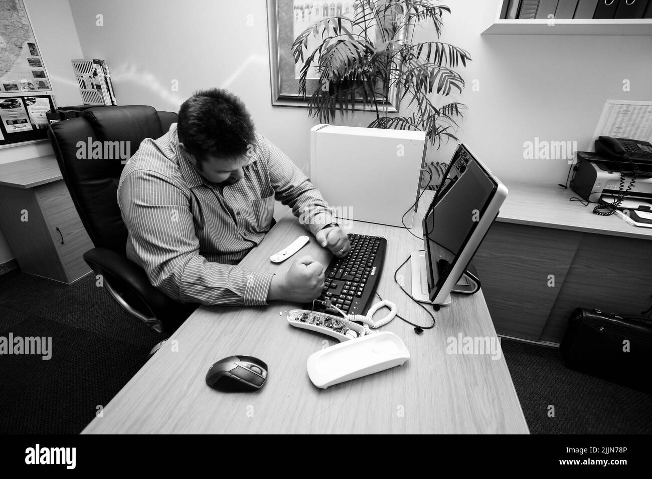 A grayscale of a Caucasian male frustrated with desktop computer in an