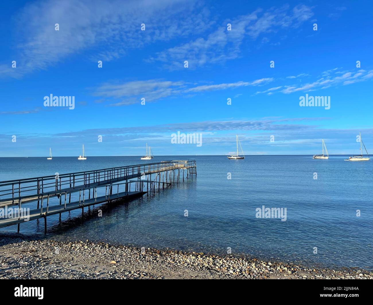 Boats anchored at sea and bathing pier on beach, Ballen, Samsoe, Jutland, Denmark Stock Photo