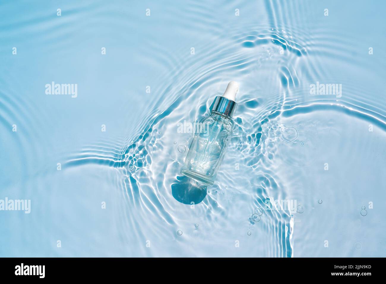 Serum, essence with collagen in transparent bottle with a pipette on water blue background Stock Photo
