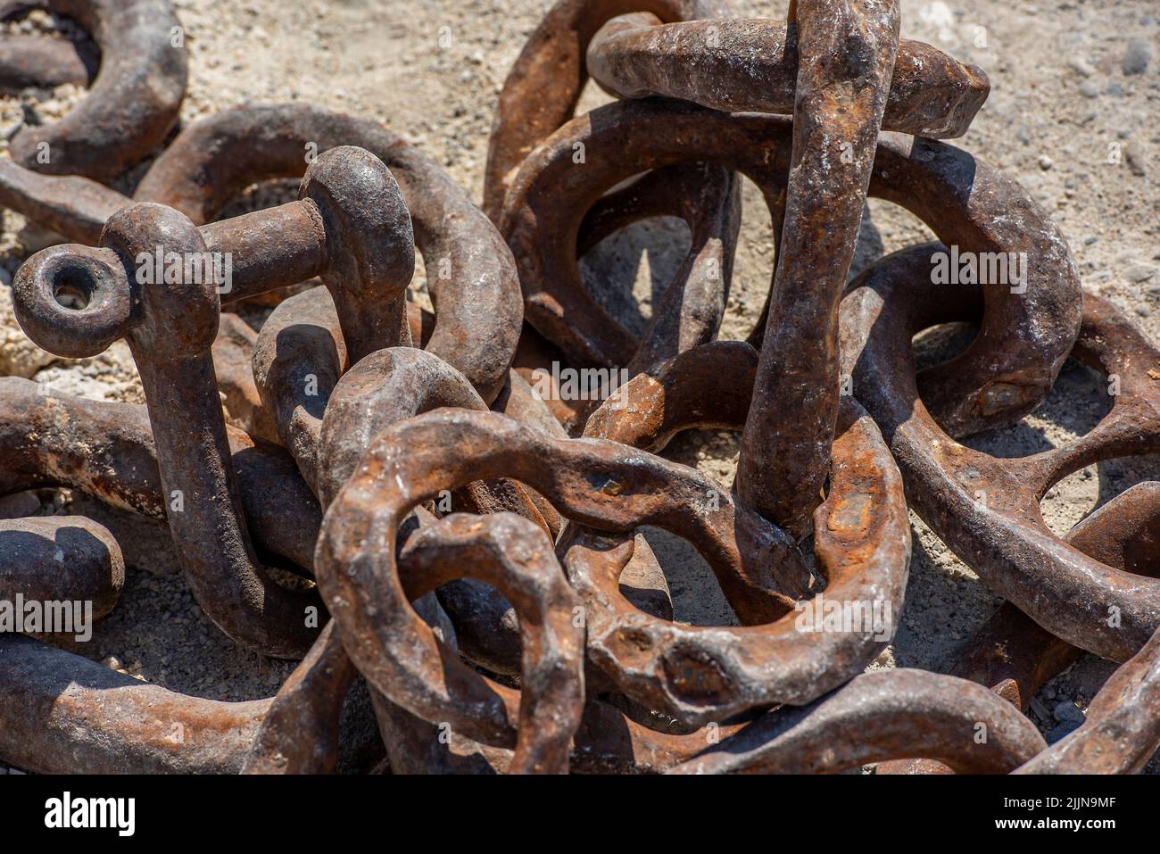 pile of rusty old chains, corroded old chains, shackles and chains on quayside, corrosion and rust on old chain links and shackles on the dockside. Stock Photo