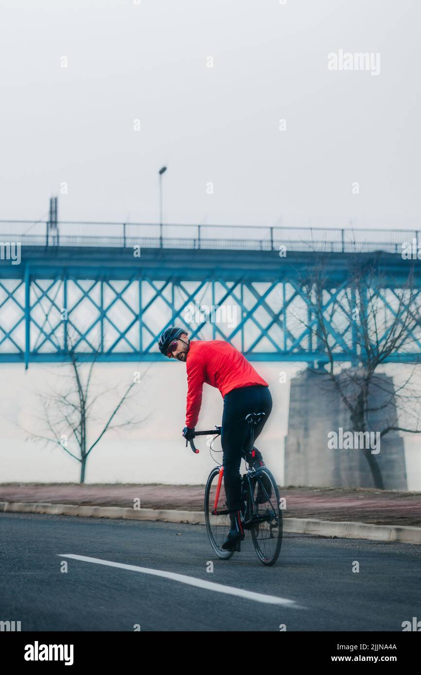 A cyclist in winter clothes rides a bike on a foggy day Stock Photo