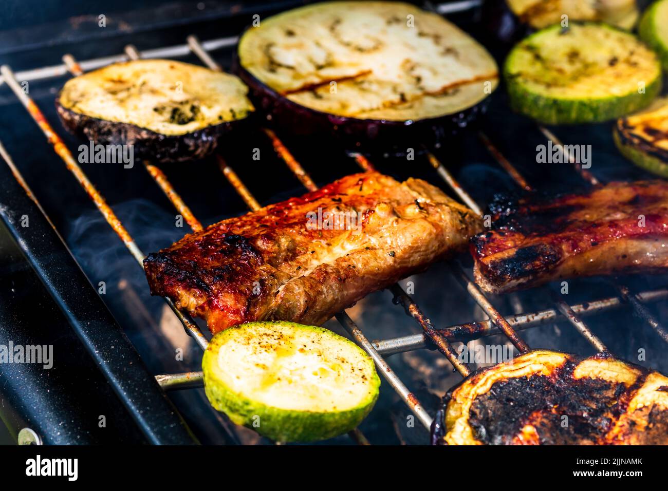 Grilling meat rolls called mici or mititei with vegetables on char barbecue Stock Photo
