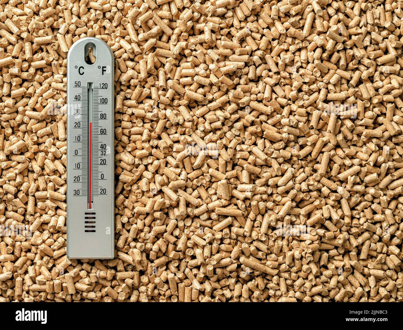 Air thermometer over wood pellets background. Ecological home heating with organic biofuel from compressed sawdust. Alternative renewable energy. Stock Photo
