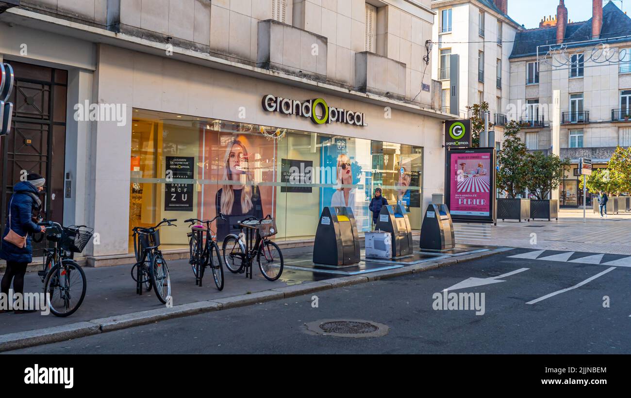 Some people walking next to The Grand Optical Optician front store facade view with logo and signage. Stock Photo
