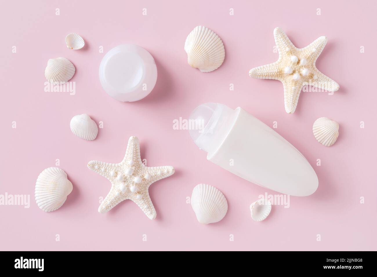 Roll on deodorant antiperspirant, sea stars and shells over pastel pink background. Sea minerals toiletries and cosmetics for body care. Toiletries. Stock Photo