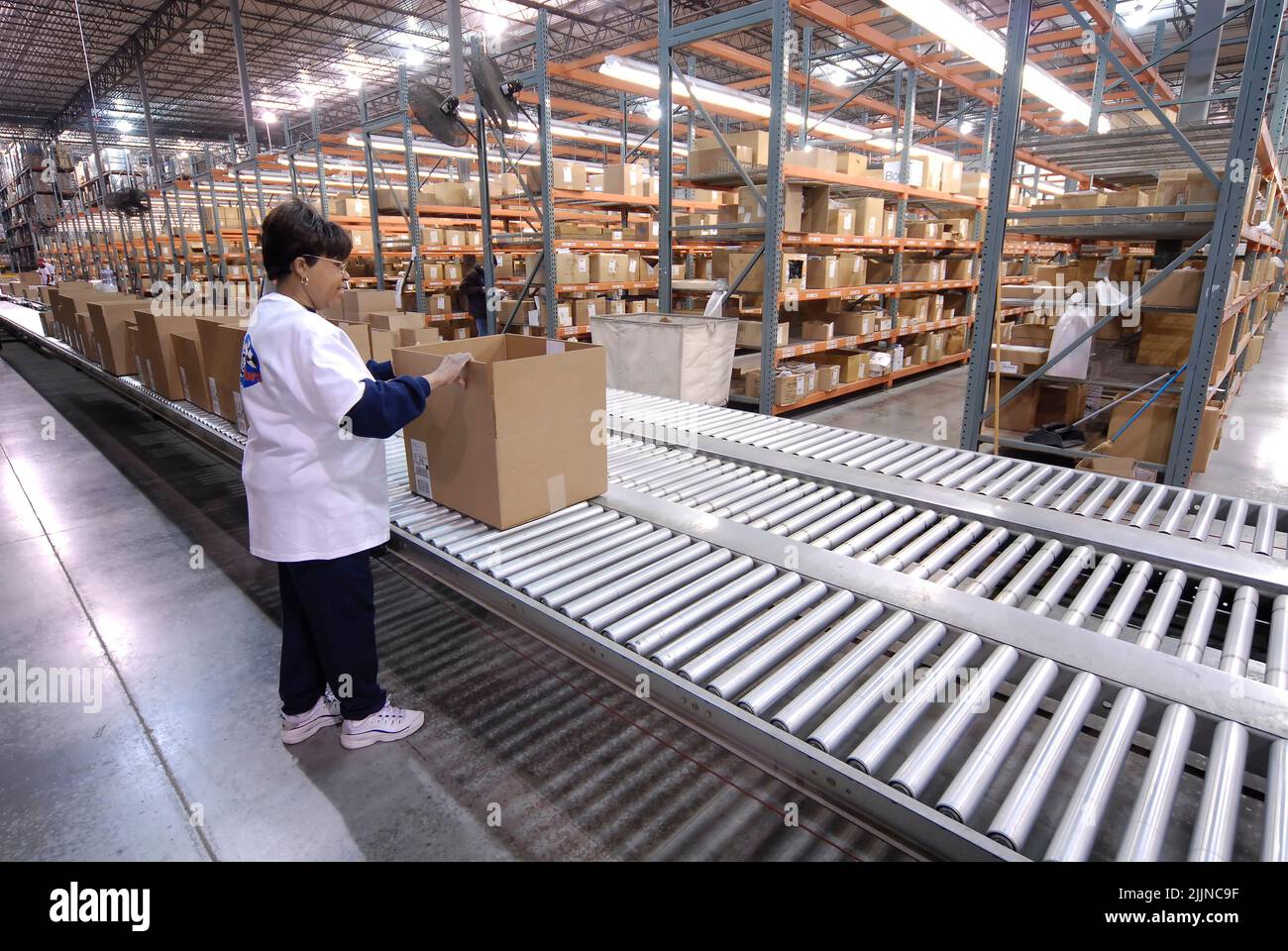 A warehouse worker handling packages on a conveyor belt line in Saint