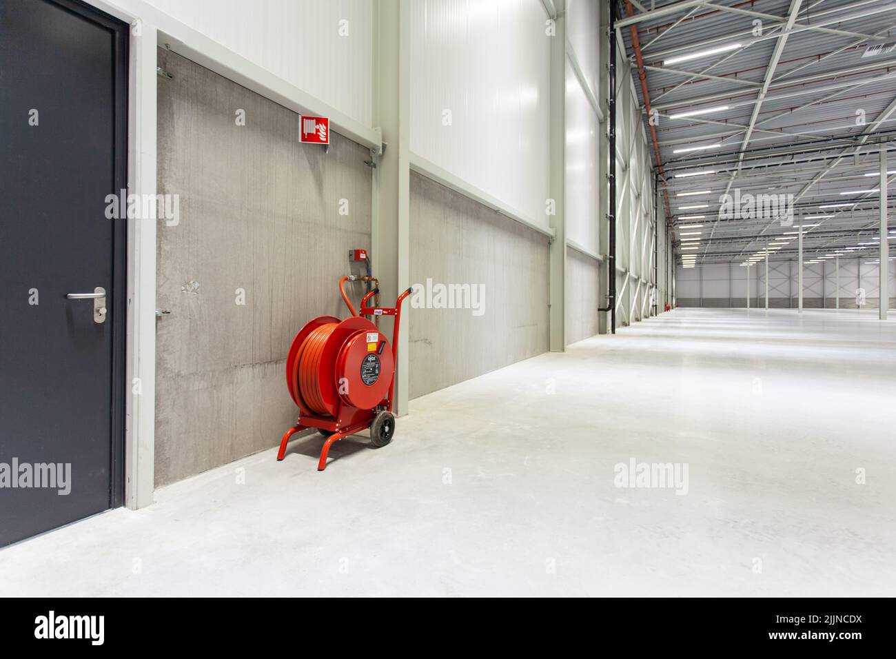 A red fire hose in a new empty warehouse Stock Photo Alamy