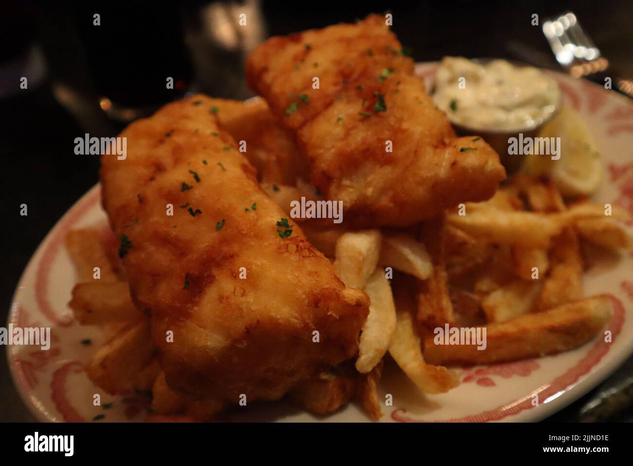 A closeup of a fish and chips dish with tartar sauce and lemon Stock Photo