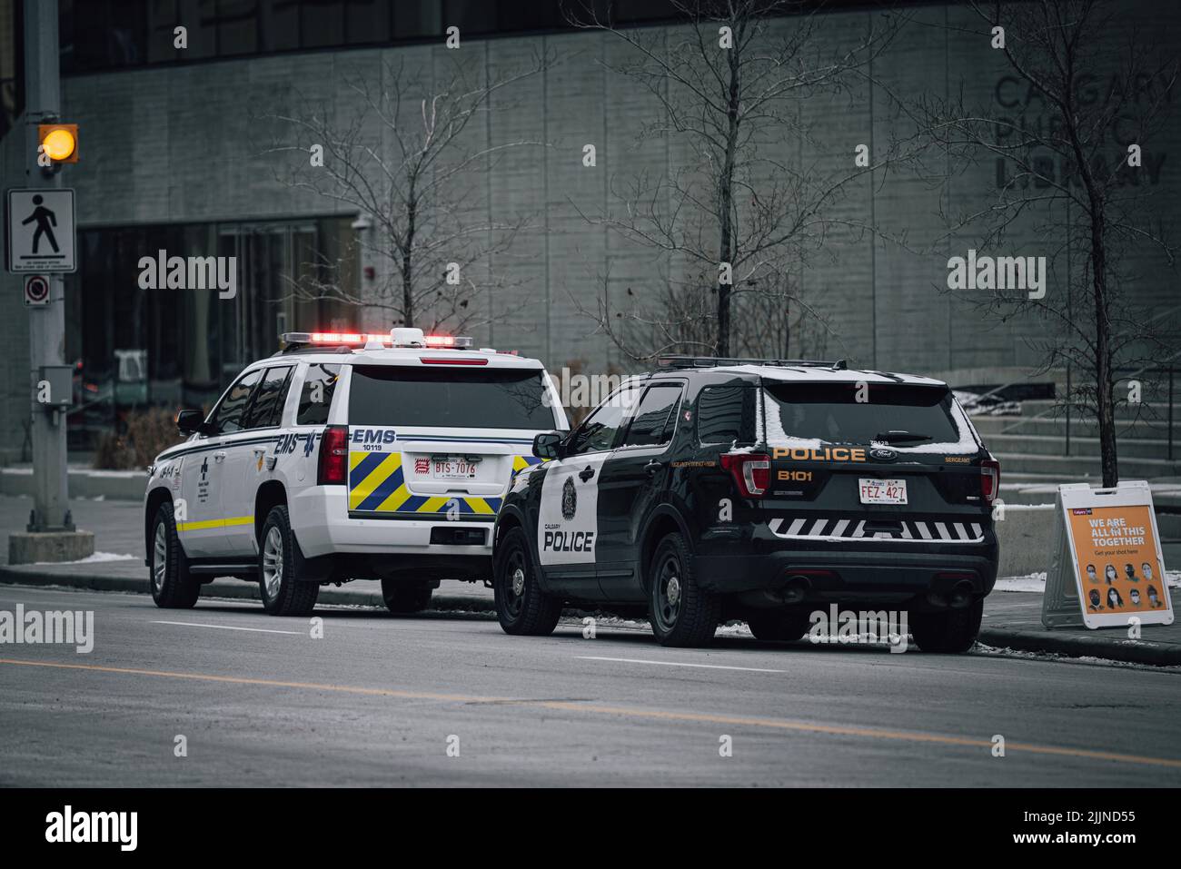 An Emergency Medical Technician vehicle parked in front of a Police vehicle Stock Photo