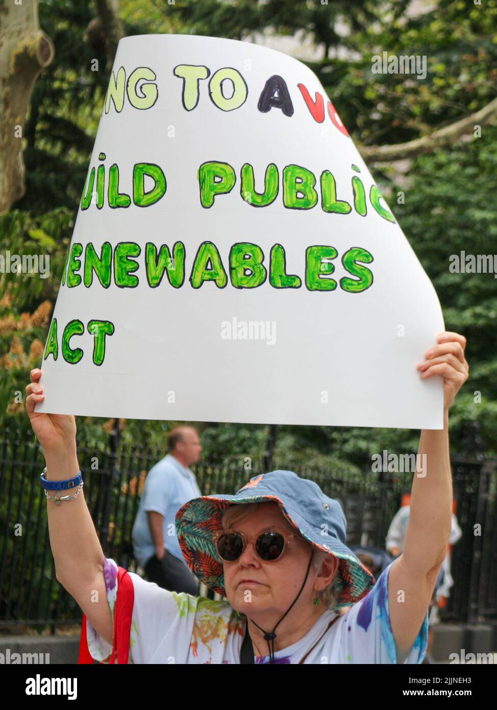Demonstrator holds a sign in front of the City Hall in New York City demanding public renewables for climate justice on July 27, 2022. Stock Photo