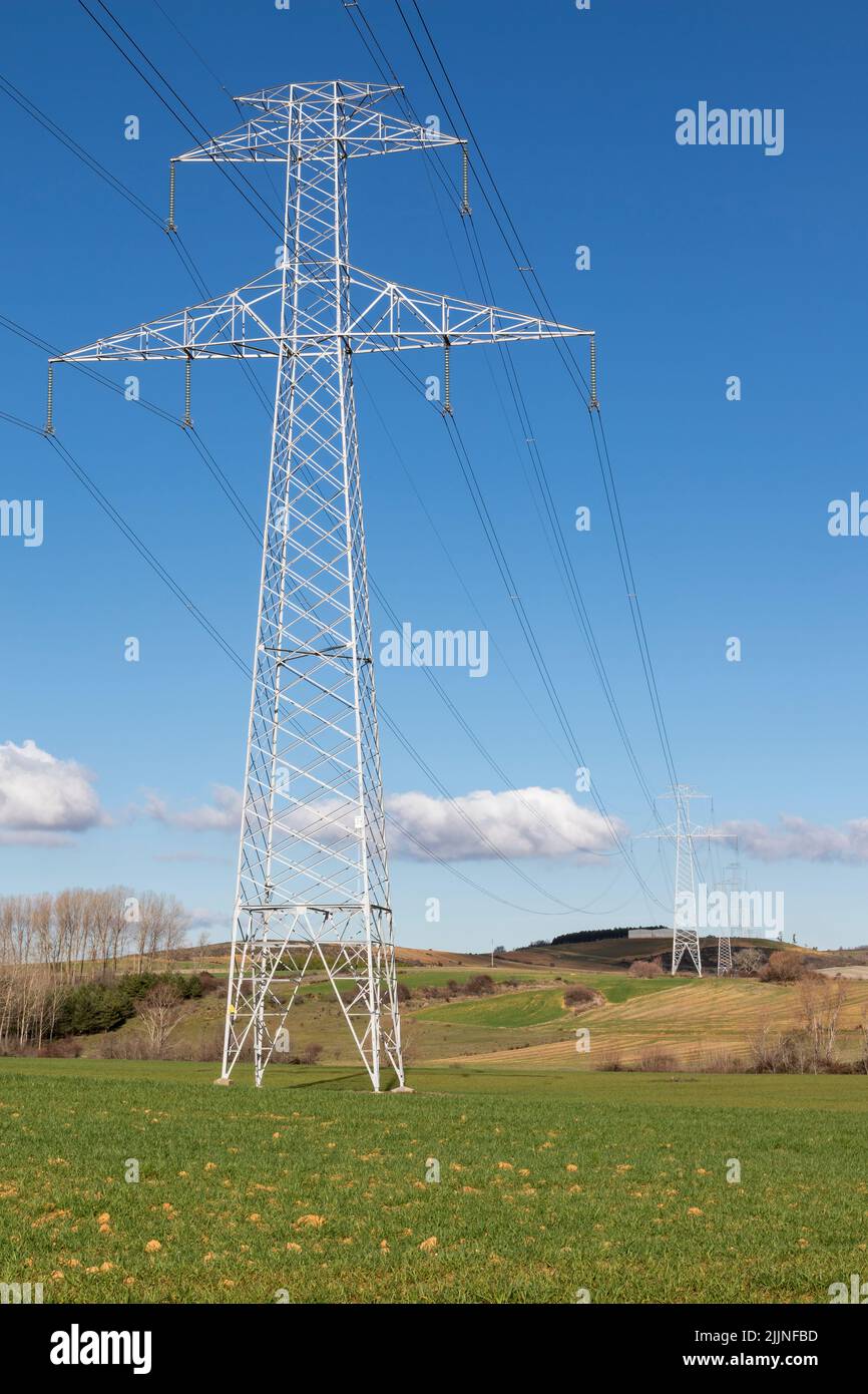 Electric pole, electricity tower station over blue sky and clouds. Vertical format Stock Photo