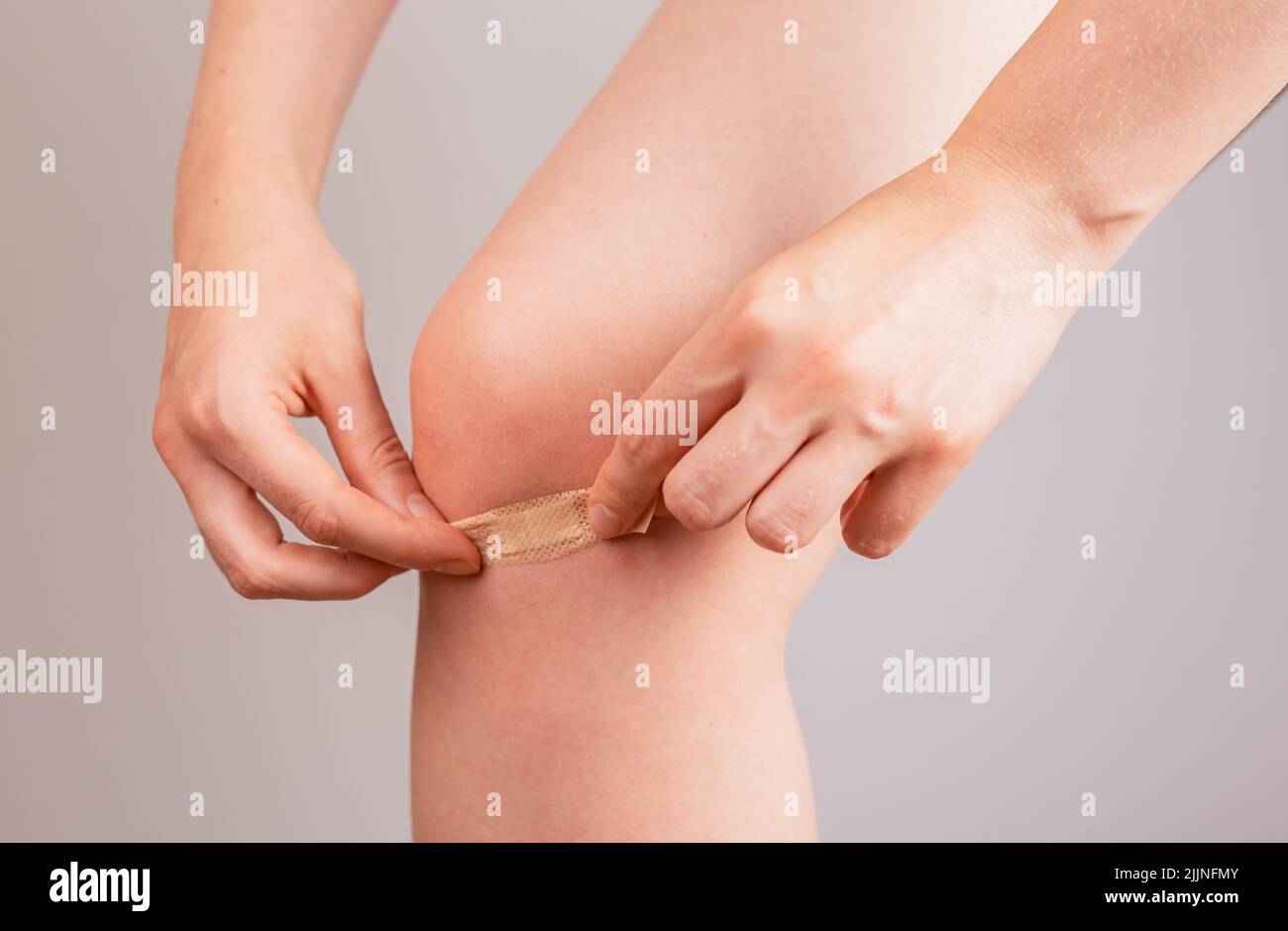 Woman applying medical plaster on knee. First aid concept. Cuts, abrasions and lightly bleeding wounds healing. Health care. Female leg closeup. High quality photo Stock Photo