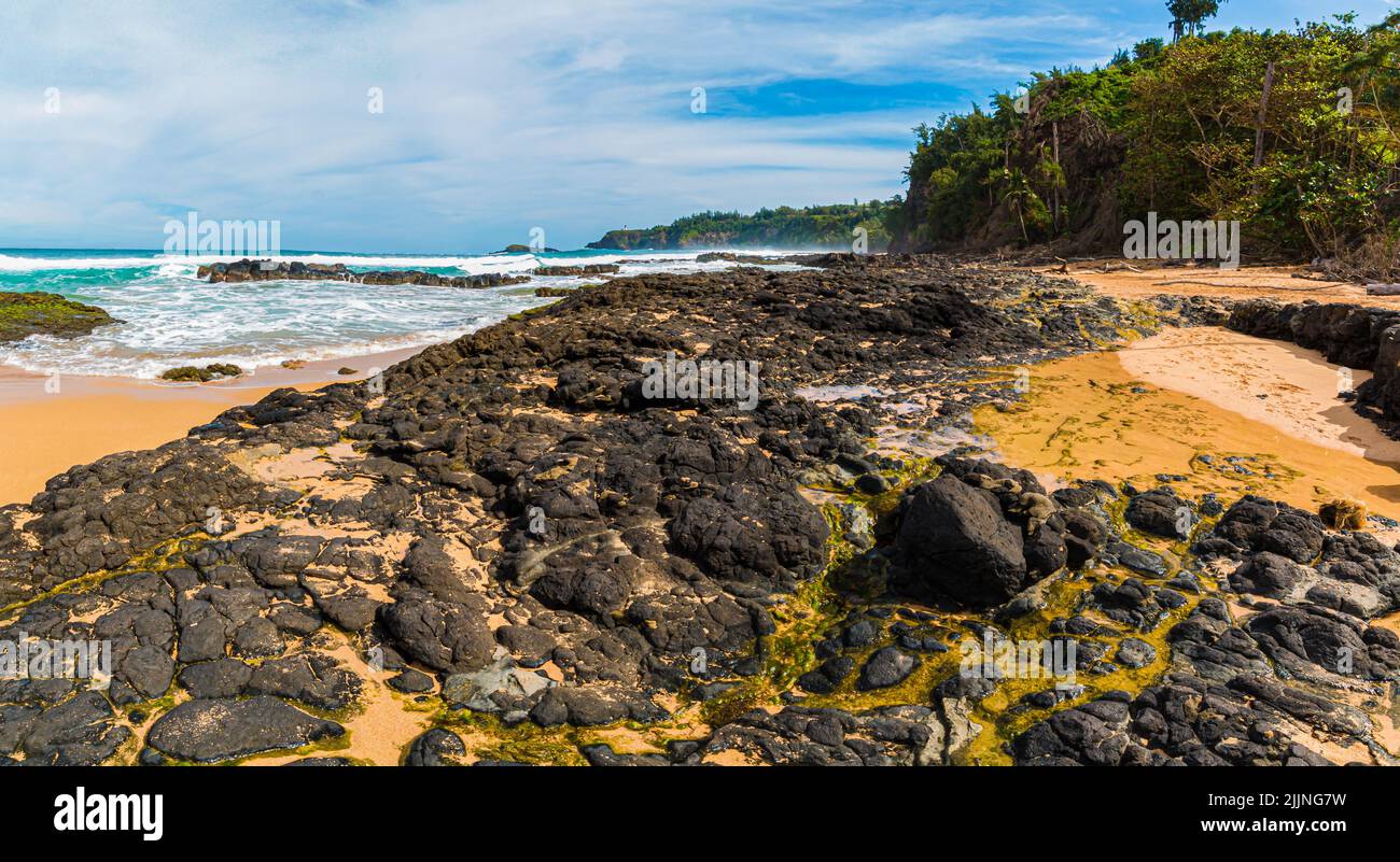Waves Crash Over Exposed Coral Reef With Kilauea Lighthouse in The Distance, Kauapea Beach, Kauai, Hawaii, USA Stock Photo