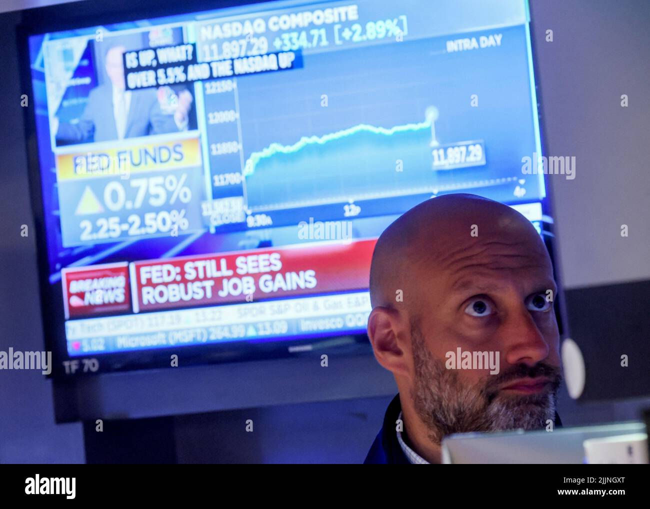A screen displays the Fed rate announcement as a trader reacts on the floor of the New York Stock Exchange (NYSE) in New York City, U.S., July 27, 2022. REUTERS/Brendan McDermid Stock Photo