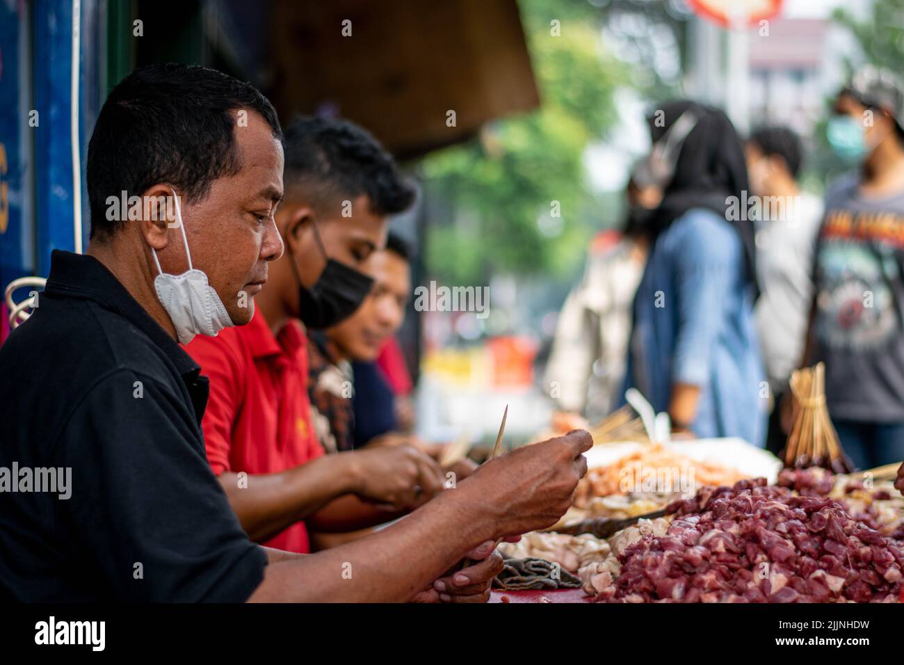 A group of street cooks prepping a variety of skewered meat Stock Photo
