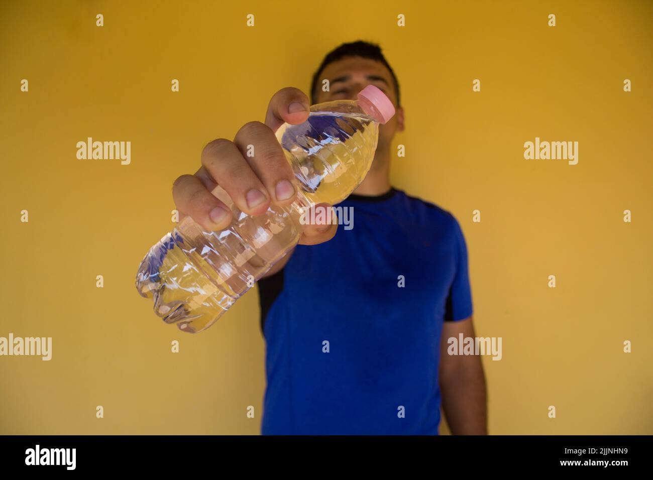 Image of a man holding a bottle of water after playing sports. Importance of hydration in the summer. Stock Photo