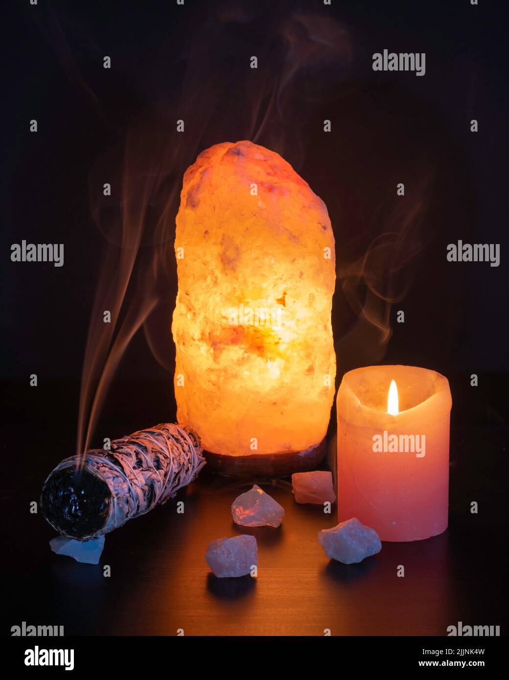 A vertical shot of the burning sage with candle and crystals in the