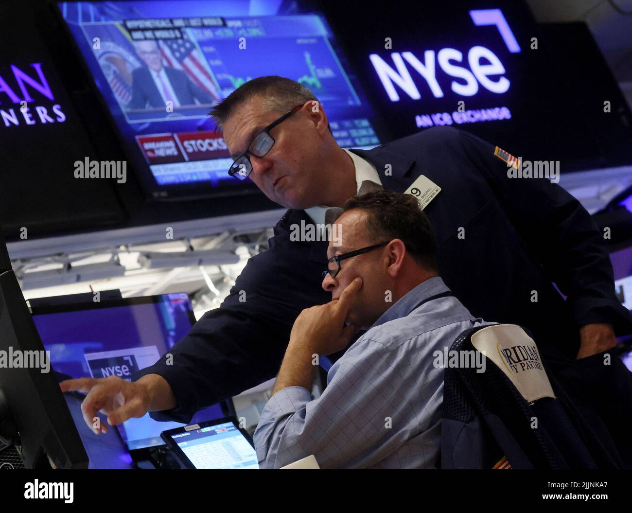 Traders work on the floor of the New York Stock Exchange (NYSE) as a screen shows Federal Reserve Board Chairman Jerome Powell during a news conference following a Fed rate announcement, in New York City, U.S., July 27, 2022. REUTERS/Brendan McDermid Stock Photo